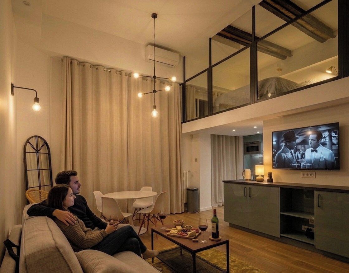 A modern living room with a sofa, a dining table, and a television.