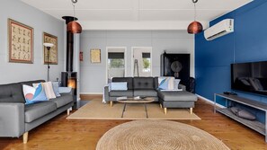 Un salon moderne avec une cheminée, un canapé, un téléviseur et des œuvres d’art.