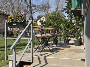 Un patio con una mesa y sillas, rodeado de plantas en macetas y una escalera.