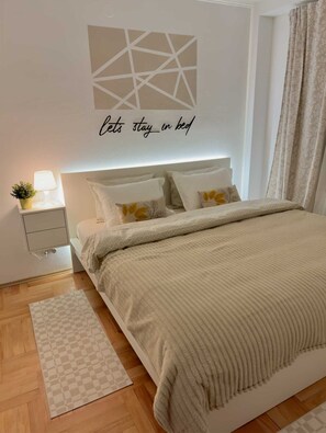 A neatly arranged bedroom with a bed, bedside table, lamp, and decorative pillow.