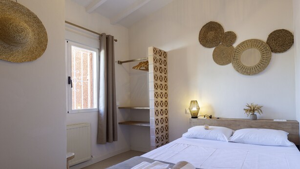 Une chambre à coucher comprenant un lit, des serviettes, une fenêtre avec des rideaux, un radiateur et des éléments de décoration murale.