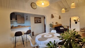 Un espace repas avec une table ronde, des chaises et une cuisine en arrière-plan.