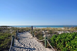 A sandy beach path leading to the ocean, with a wooden fence and rope barrier. - Gulf & Greenbelt Views, No-Expense-Spared Remodel, Seaplace Oasis (Longboat Key)