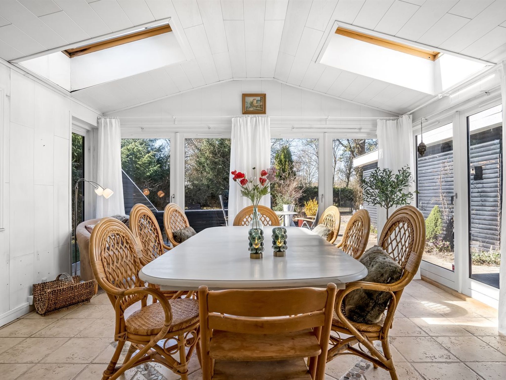 Un espace repas avec une table ronde, des chaises en osier et une vue sur l’extérieur.