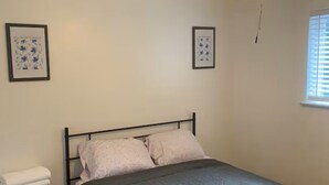 Una camera da letto con un letto, un comodino, una ventola a soffitto e due quadri appesi al muro.