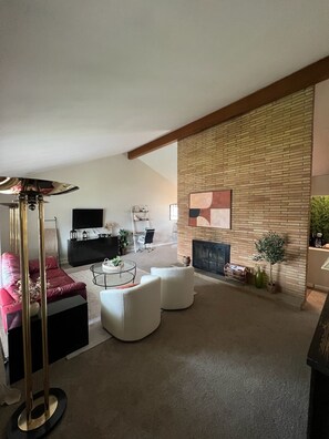 A modern living room with a sofa, armchairs, a coffee table, a TV, and a fireplace.