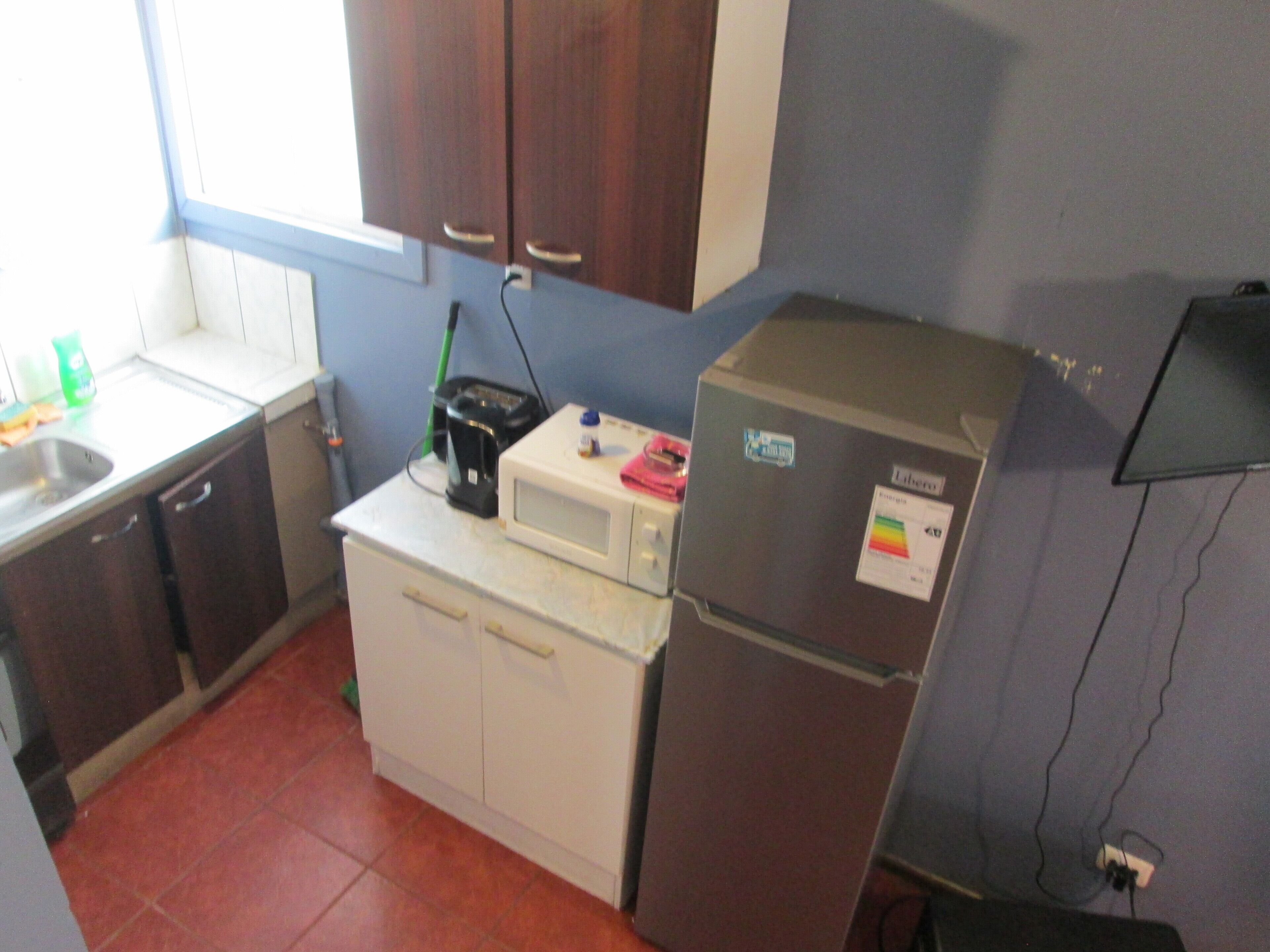 A compact kitchen with a microwave, a refrigerator, and a sink.