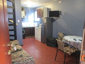 Cocina compacta con refrigerador, microondas y estufa. Cuenta con un comedor con mesa y sillas.
