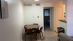 A compact living space with a dining area, kitchenette, and a door leading to another room. - 1x1 Apt Right by Pease Park (Austin)