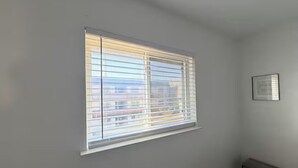 A room with a window, a framed picture on the wall, and a small table. - 1x1 Apt Right by Pease Park (Austin)