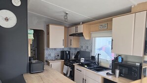 A compact kitchen with a stove, microwave, and coffee maker. - 158 South Happy Days - Sleeps 8 (Skegness)