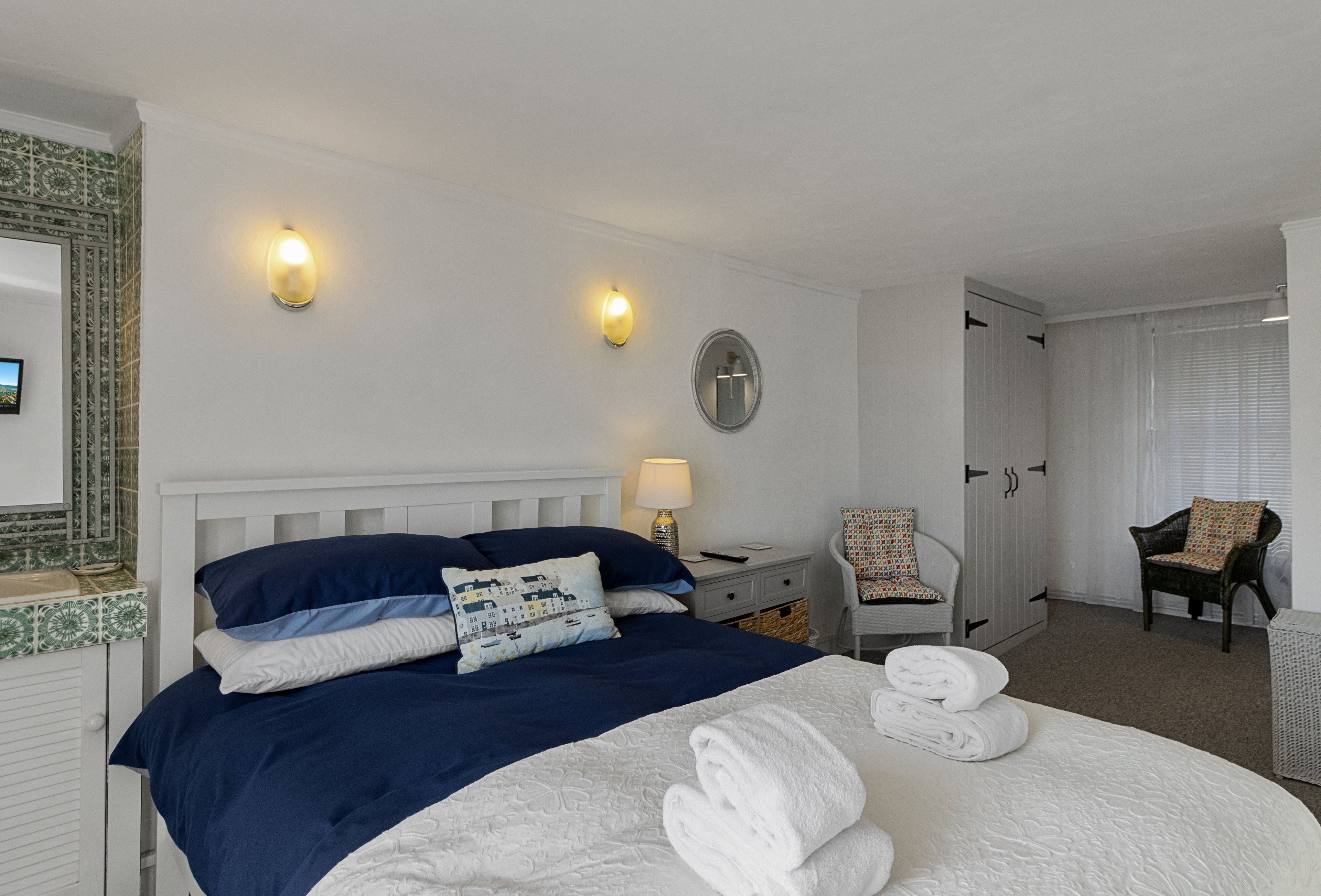 A hotel room with a bed, a nightstand, a chair, a wardrobe, and a bathroom.