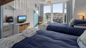 A hotel room with two beds, a television, a balcony with a view, and a wooden ceiling. - Rock Cottage is a charming coastal retreat (Brixham)