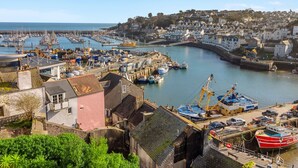 A coastal town with a marina, buildings, and a curved harbor wall. - Rock Cottage is a charming coastal retreat (Brixham)