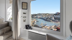 A room with a large window offering a view of a harbor, a radiator, and a framed certificate on the wall. - Rock Cottage is a charming coastal retreat (Brixham)