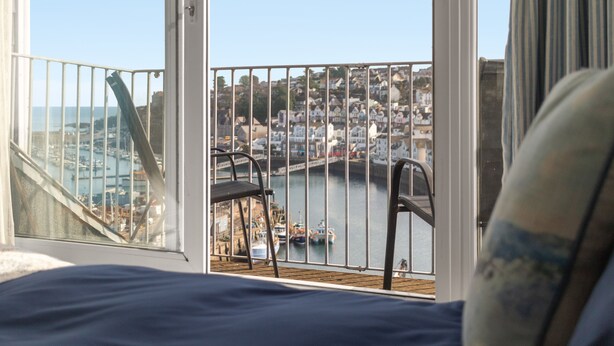 A balcony with a view of a harbor, a chair, and a railing. - Rock Cottage is a charming coastal retreat (Brixham)
