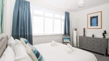 Ein Hotelzimmer mit einem Bett, einem Schminktisch, einem Spiegel und einem Fenster mit Vorhängen.