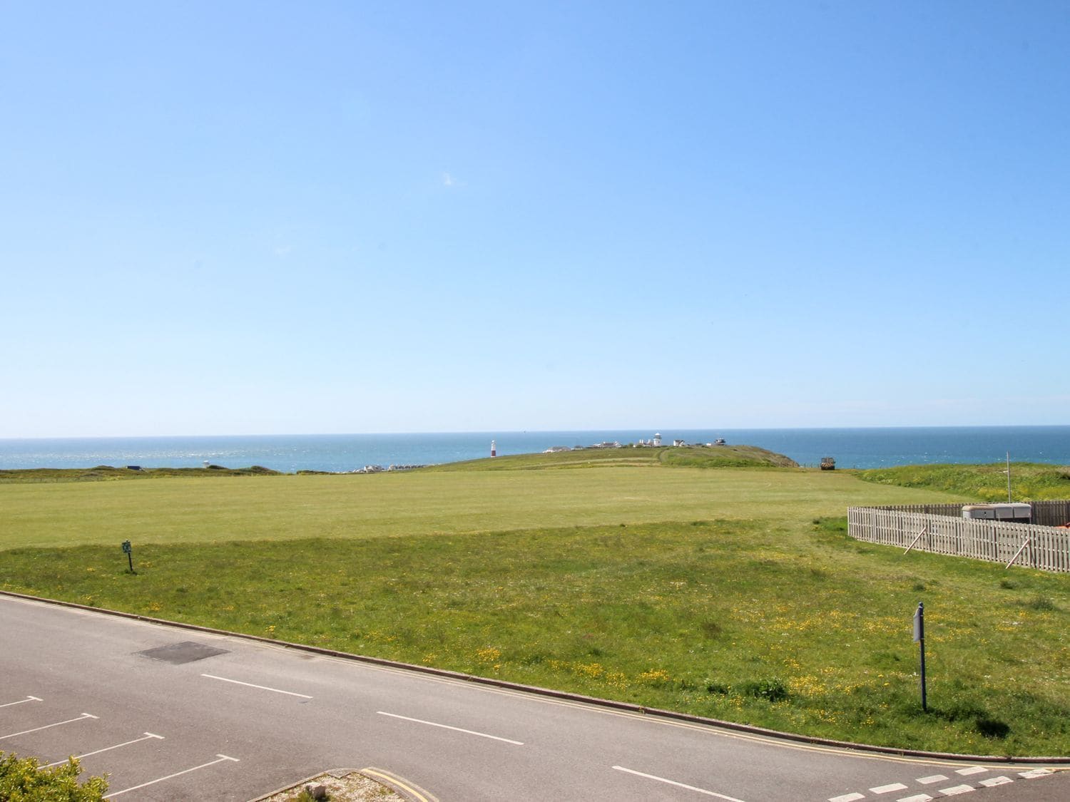 Una strada costiera con una zona verde e vista sul mare.