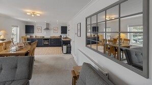 Une cuisine moderne avec des meubles de rangement de couleur sombre, un coin repas avec des meubles en bois et une grande fenêtre offrant une belle vue.