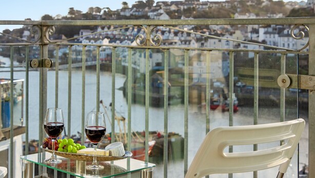 A balcony with a glass table, two wine glasses, a plate with grapes, and a chair. - Prime central location at Harbour Heights in Brixham (Brixham)