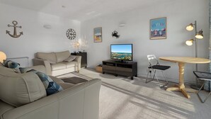 A living room with a sofa, a coffee table, a TV, and a dining area with a table and chairs. - Prime central location at Harbour Heights in Brixham (Brixham)