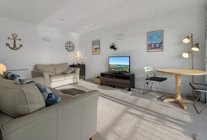 A living room with a sofa, a coffee table, a TV, and a dining area with a table and chairs. - Prime central location at Harbour Heights in Brixham (Brixham)