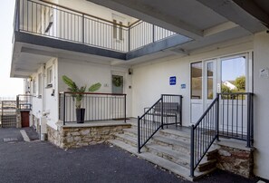 Un edificio de dos plantas con base de piedra y un balcón en el piso superior.