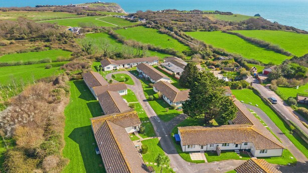 A coastal residential area with houses, a road, and a view of the sea. - Landscove Chalet 19 a charming and cosy South Devon holiday cottage (Brixham)