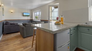 A modern kitchen with a central island, wooden flooring, and green cabinetry. - Landscove Chalet 19 a charming and cosy South Devon holiday cottage (Brixham)