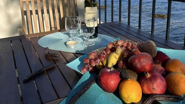 Ein Tisch mit einer Weinflasche, Gläsern und verschiedenen Früchten auf einer blauen Unterlage.