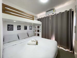 A bunk bed room with a white headboard, a flat-screen TV, and a wall-mounted air conditioner. - Nik Vila Mariana (São Paulo)