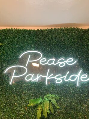 A neon sign with the text 'Rease Parkside' against a backdrop of green foliage. - Lovely 1x1 Apt by Pease Park (Austin)