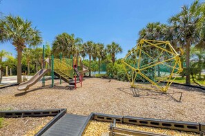 A playground with a slide, climbing structures, and a yellow climbing frame. - Cozy Disney Getaway 2BR  5 Mins to Parks (Kissimmee)