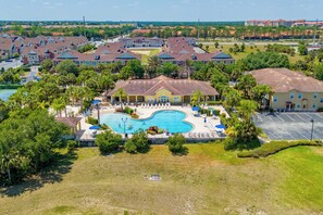 A residential area with a swimming pool surrounded by houses and greenery. - Cozy Disney Getaway 2BR  5 Mins to Parks (Kissimmee)