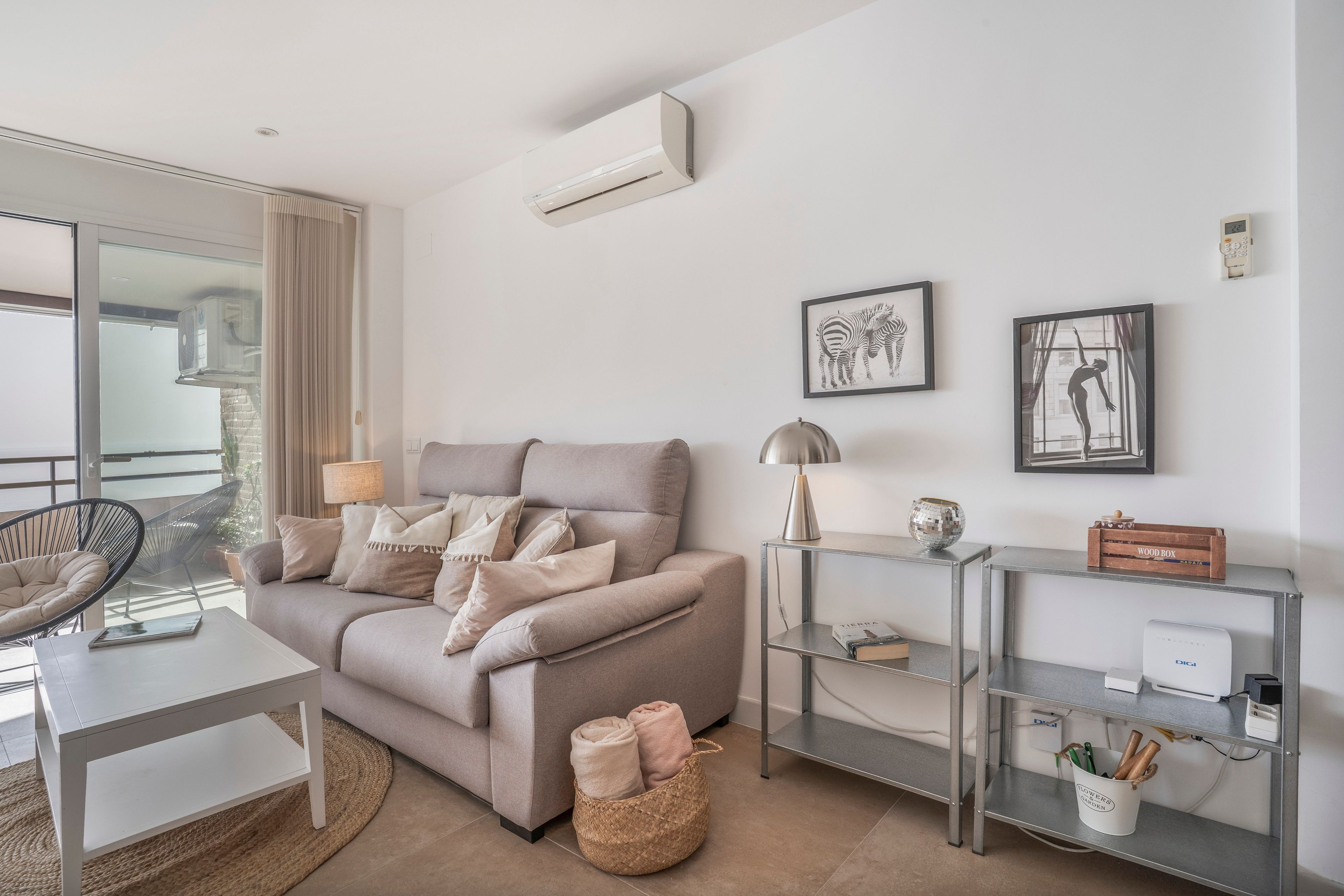A modern living room with a sofa, a coffee table, a side table, and a wall-mounted air conditioner.