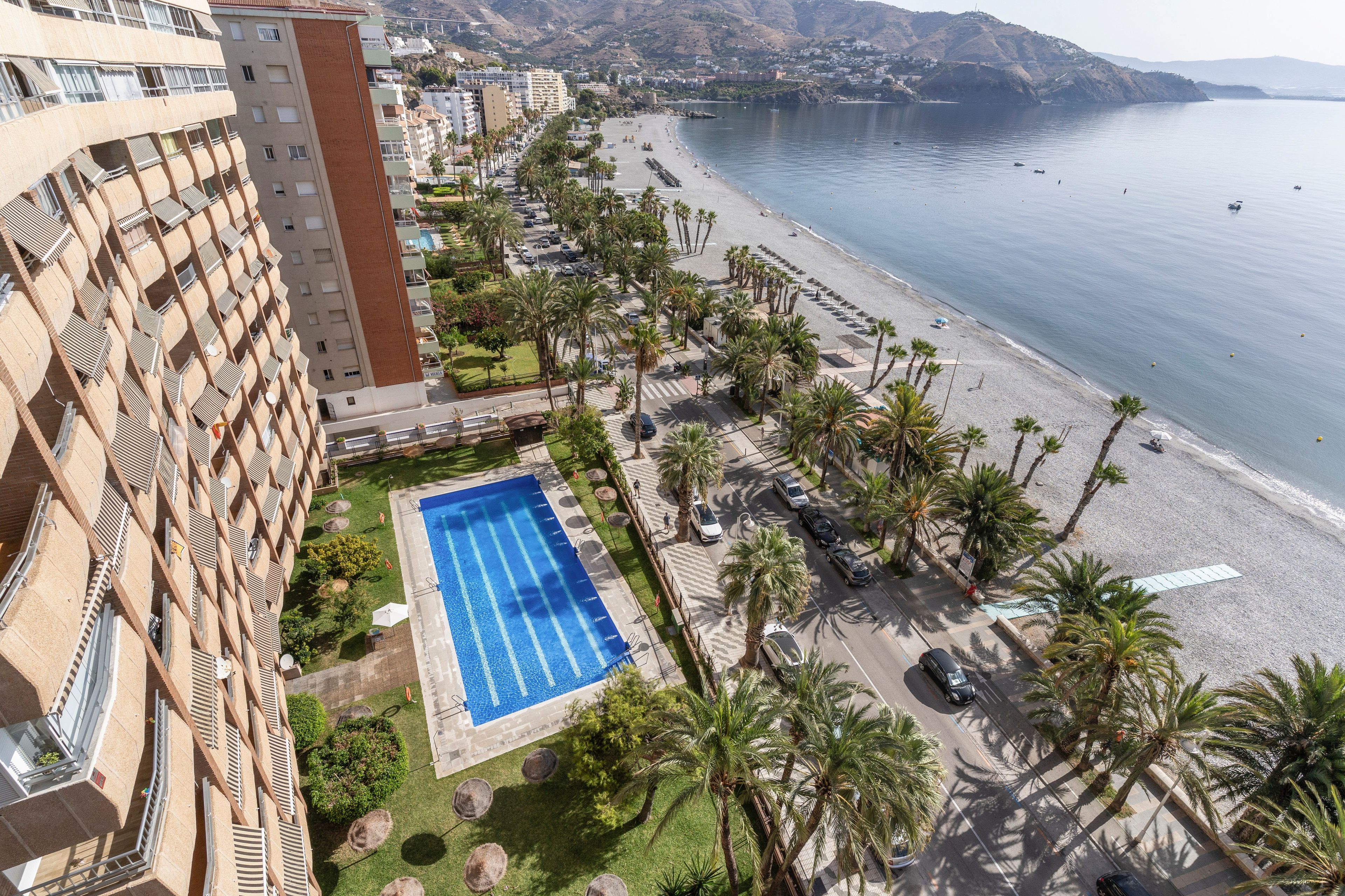 A high-rise hotel with a swimming pool, beach access, and a view of the sea.