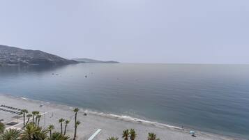 Una playa con cielo despejado, mar tranquilo y algunas personas.