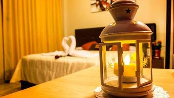 A room with a bed, a nightstand, and a table with a candle in a lantern.