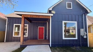 A two-story house with a red door, a covered porch, and a small window. - Modern Stay Next to Downtown  Sleeps 7 (San Antonio)