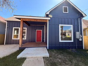 A two-story house with a red door, a covered porch, and a small window. - Modern Stay Next to Downtown  Sleeps 7 (San Antonio)