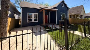 A residential house with a front porch, a red door, and a fenced yard. - Modern Stay Next to Downtown  Sleeps 7 (San Antonio)