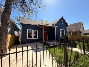 A residential house with a front porch, a red door, and a fenced yard. - Modern Stay Next to Downtown  Sleeps 7 (San Antonio)