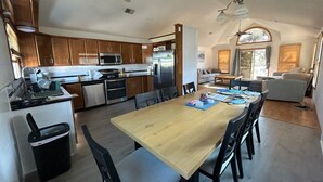 Una cucina moderna con mobili in legno, elettrodomestici in acciaio inossidabile e un'area pranzo con tavolo e sedie in legno.