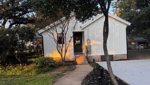 A white building with a front door, a small porch, and a pathway leading to the entrance. - Highly Rated Farm Cottage · Weatherford TX · 30 Min to Fort Worth (Weatherford)