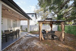 Un espace extérieur aménagé avec une pergola, une table à manger avec des chaises et un décor de jardin.