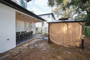 Ein überdachter Patio-Bereich mit Tisch und Stühlen, einer Lichterkette und einer großen Zeltdach-Konstruktion.