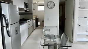A modern kitchen with stainless steel appliances, a glass dining table, and a minimalist design. - 802 santa elena (Medellín)