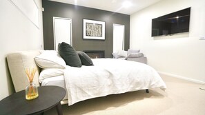 Una camera da letto moderna con un letto, un tavolino con una candela, un camino e una TV a parete.