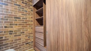 A brick wall and a wooden wardrobe with multiple shelves. - ¡Alberca y Gym! / Barrio W / 2 personas #Centro (Monterrey)