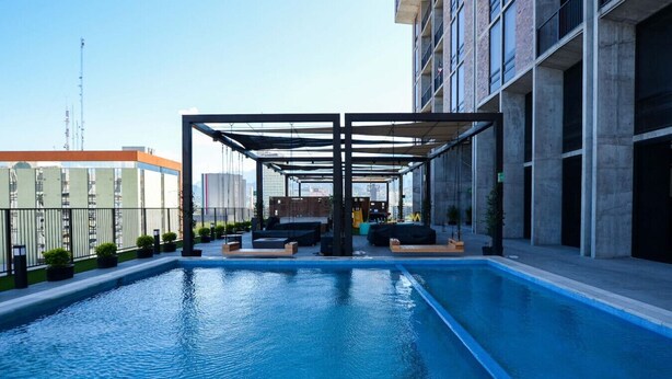 A rooftop swimming pool with a covered seating area, surrounded by modern buildings. - ¡Alberca y Gym! / Barrio W / 2 personas #Centro (Monterrey)